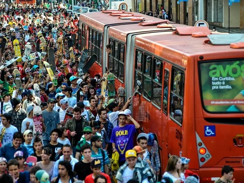 Skatistas ocupam a canaleta ao lado dos ônibus vermelhos de Curitiba